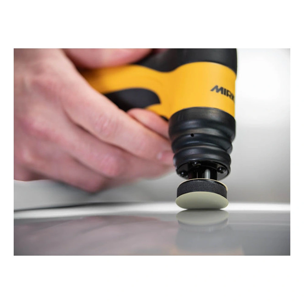 Yellow-and-black hand tool with a small round pad touching a glossy surface