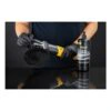 A person wearing black gloves holds a black and yellow polishing tool next