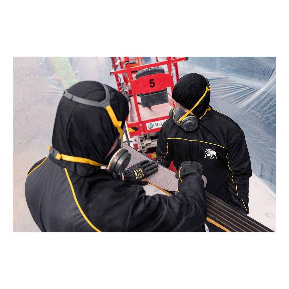 Two workers in full protective gear holding a long board with a rough
