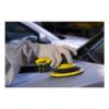 A gloved person using a yellow-and-black random orbital sander on a light