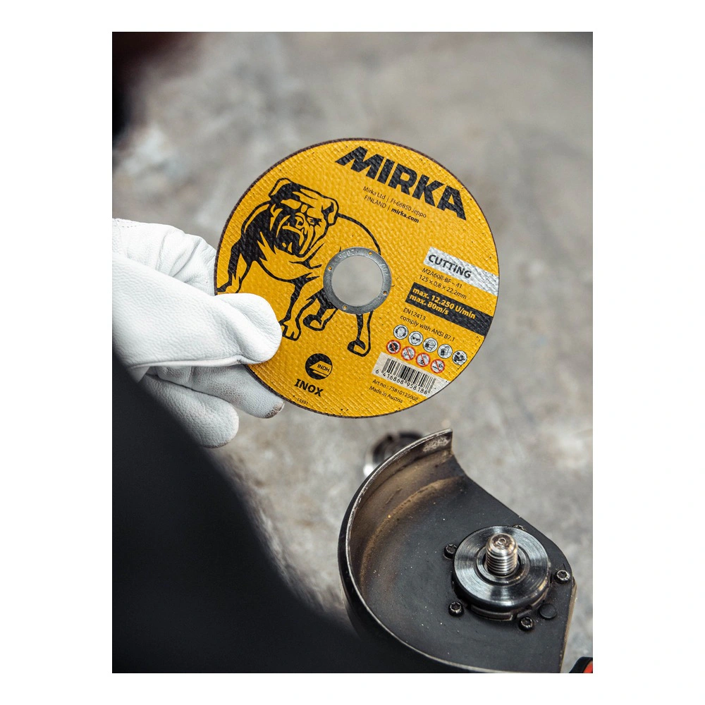 Yellow cutting disc held in glove, beside grinder