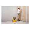 Person using a dust extractor beside a wall