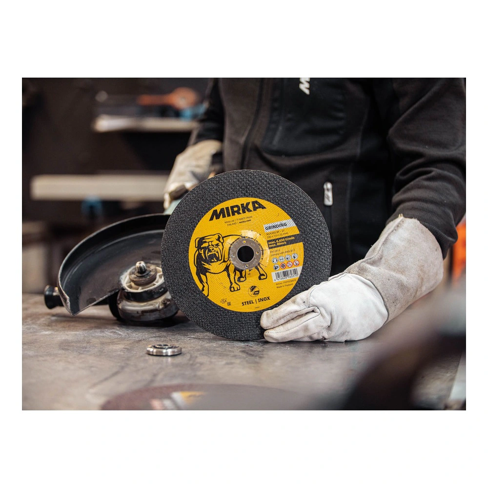 Worker holds grinding disc beside grinder