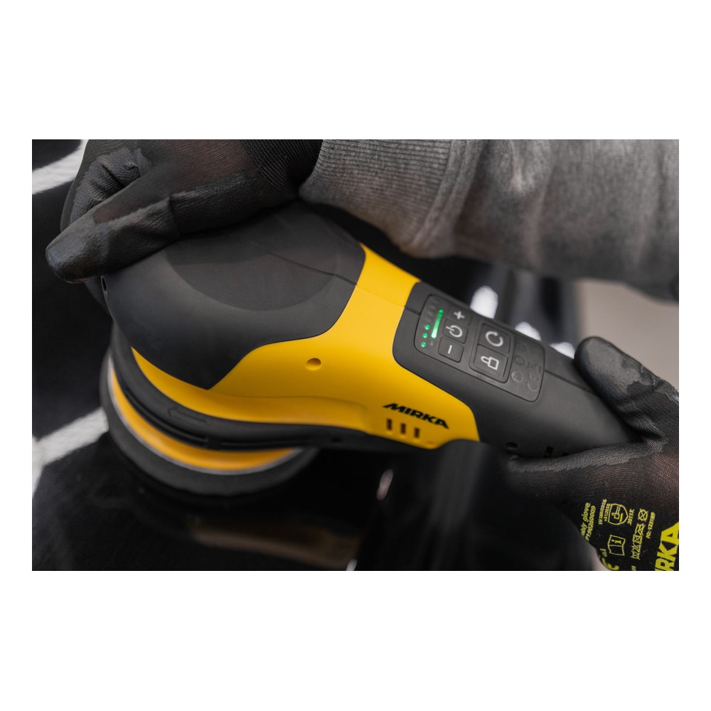 Black-yellow rotary polisher held in gloved hands