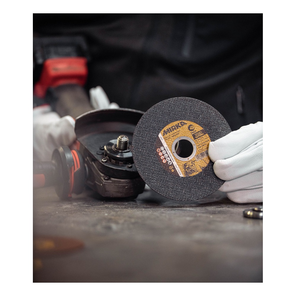 Technician holding cutting wheel beside grinder