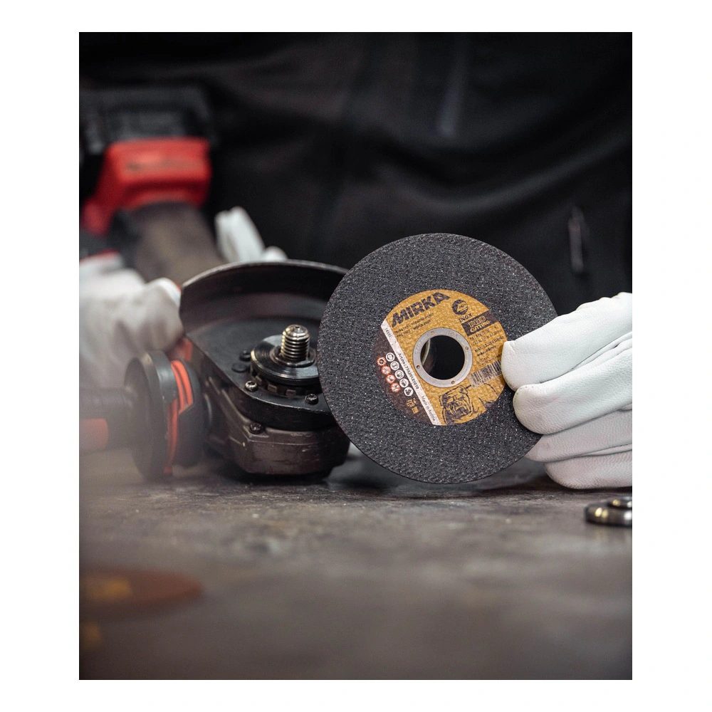 Technician holding cutting wheel beside grinder