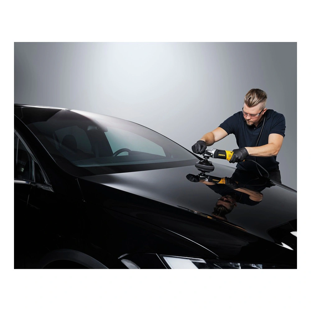 Man polishing a black car hood with machine