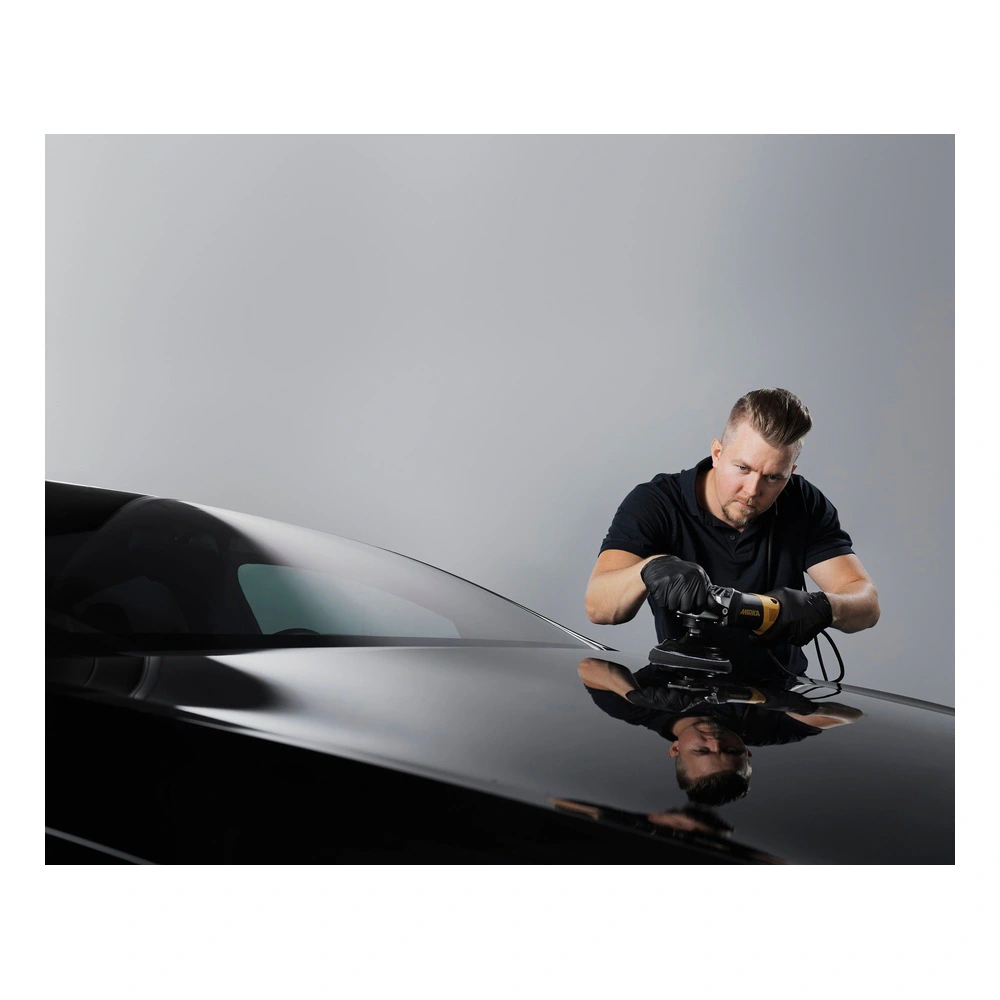 Person polishing a glossy black car hood