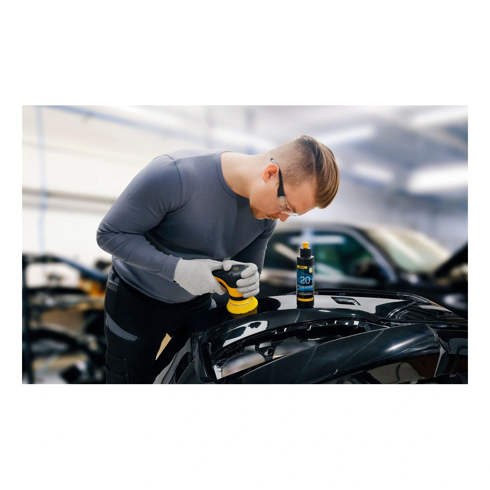 Person polishing a car hood, bottle standing nearby