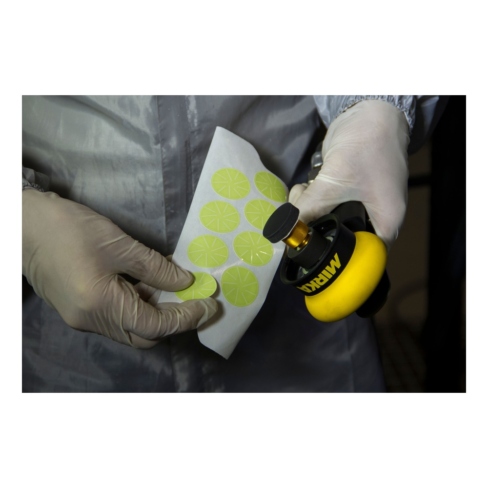 Gloved hands hold green discs and polishing tool