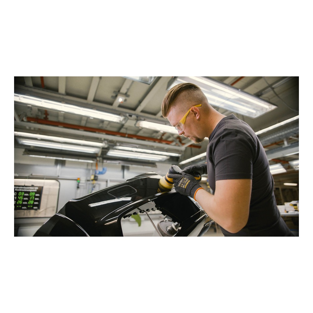 Worker polishing a black part with hand tool