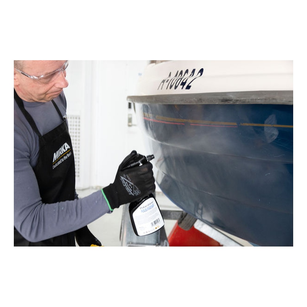 Person spraying a boat hull in workshop