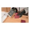 Gloved person holding pads over workbench