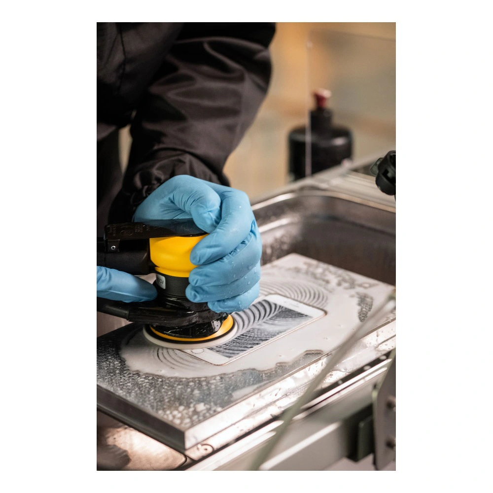 Gloved hands using polishing tool on surface