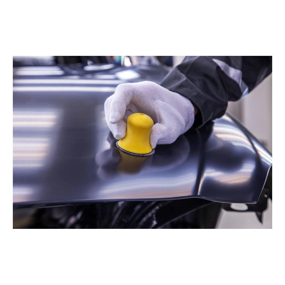 Gloved hand holding block on dark sheet metal