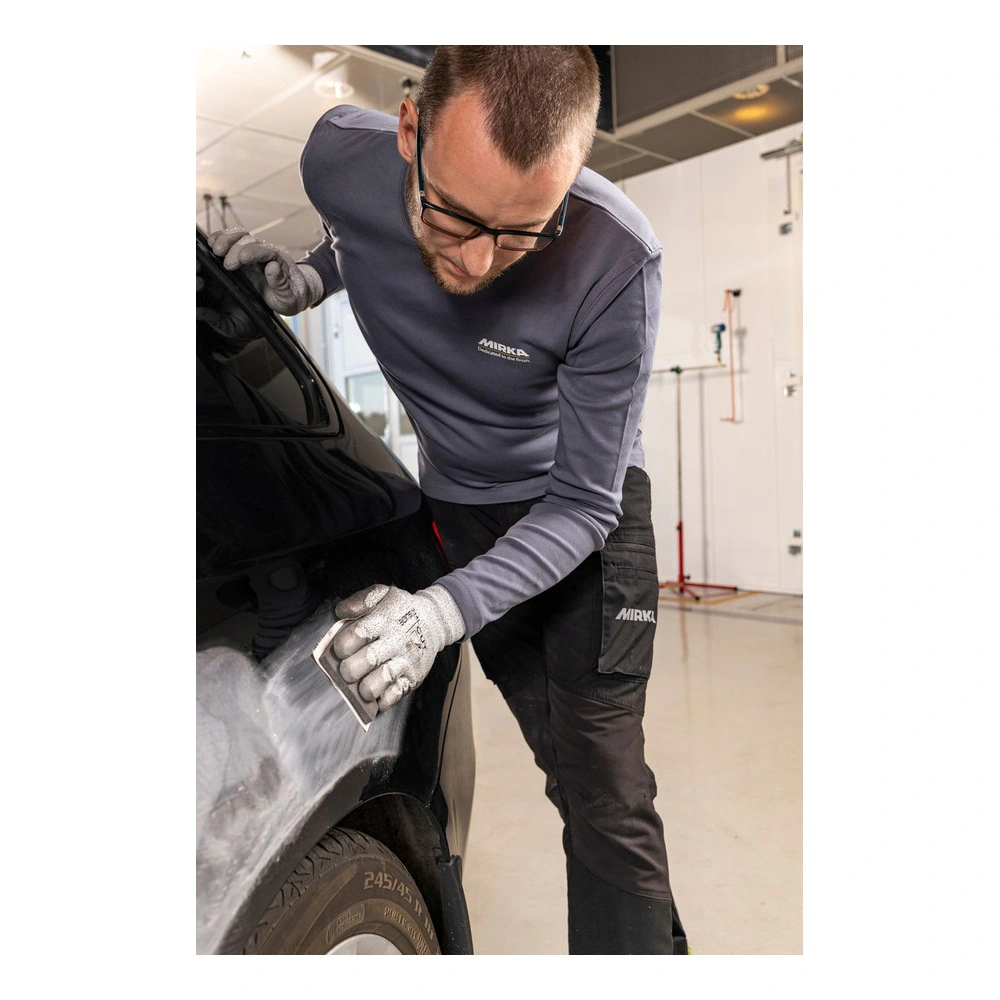 אדם משייף רכב שחור במוסך מואר