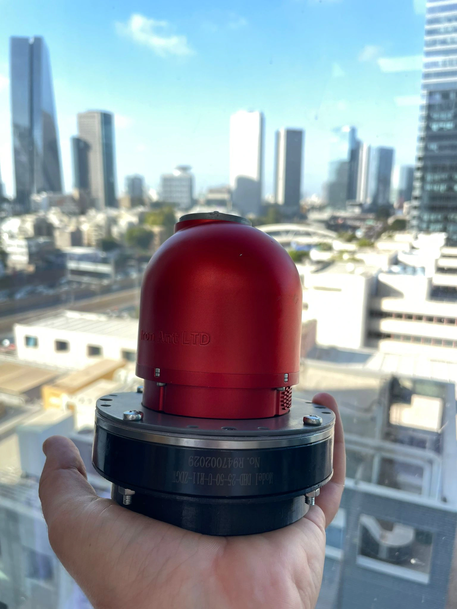 Red prototype held by hand above the city